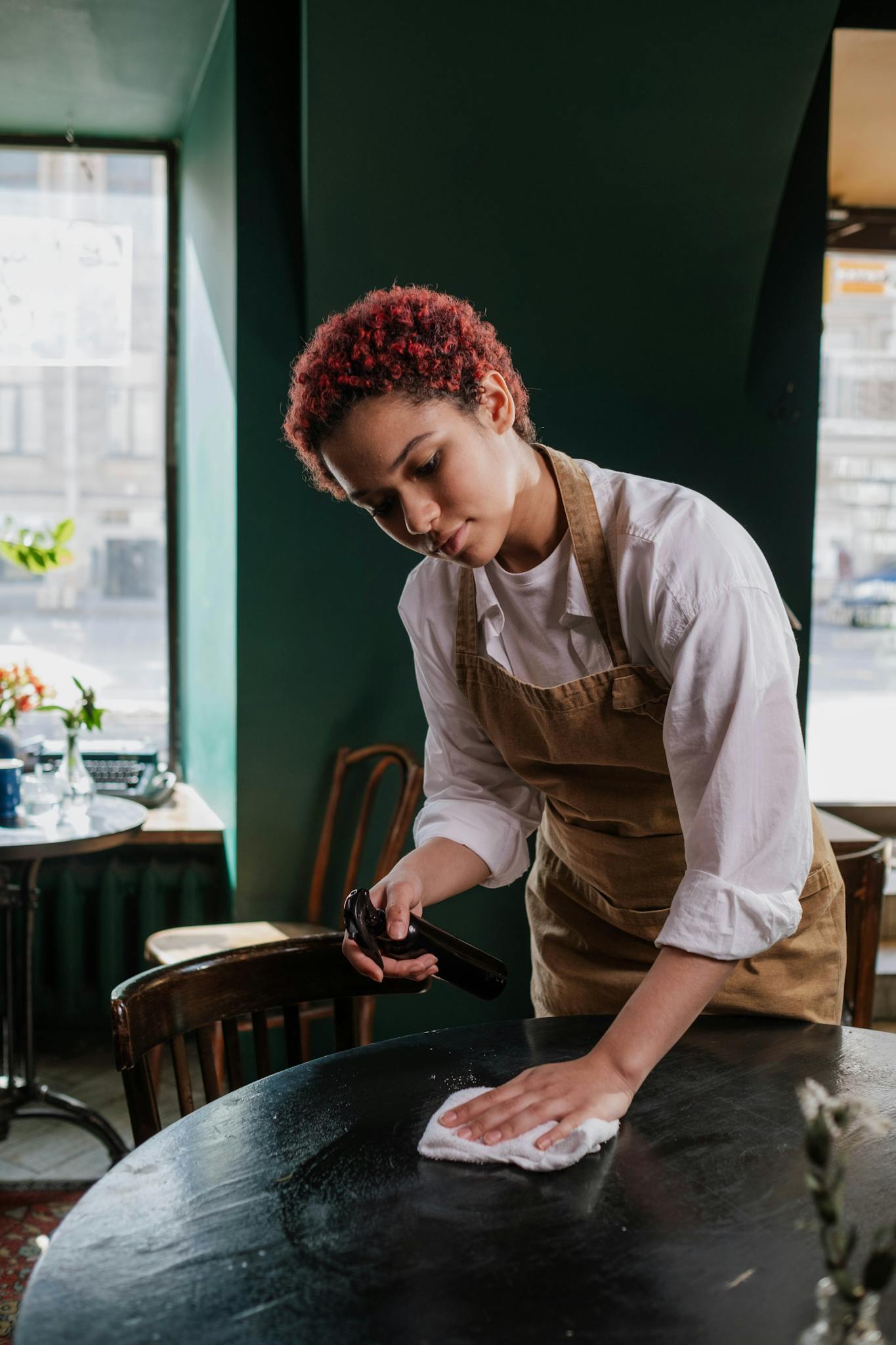 Young waitress cleans a table in a cozy café, capturing the essence of service and hospitality.